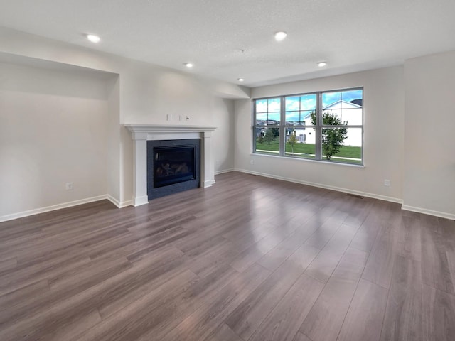 unfurnished living room featuring a textured ceiling and dark hardwood / wood-style flooring