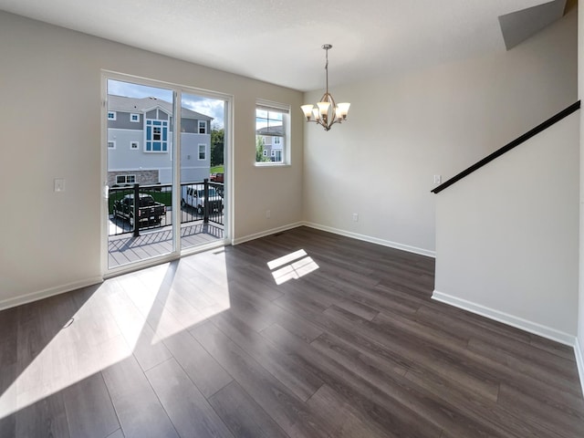 spare room featuring dark wood-type flooring and a notable chandelier