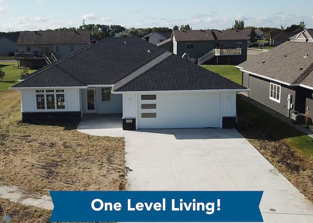 ranch-style home with a shingled roof, board and batten siding, a residential view, and a garage