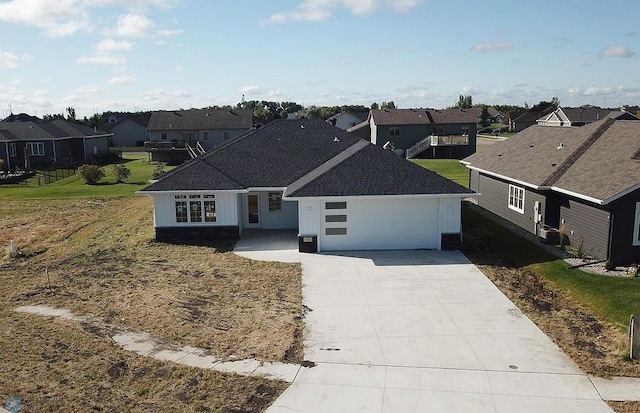 single story home with a residential view, a garage, concrete driveway, a shingled roof, and a front yard