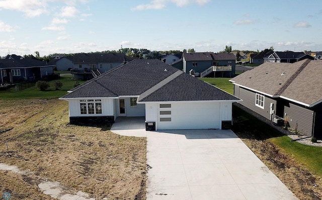 view of front facade with concrete driveway, a garage, a shingled roof, and a residential view
