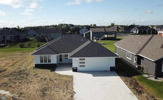 exterior space featuring driveway, an attached garage, central air condition unit, a residential view, and a shingled roof