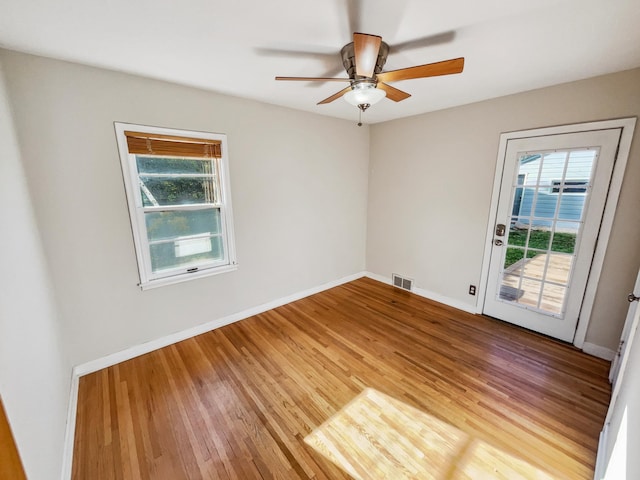 unfurnished room featuring a healthy amount of sunlight, hardwood / wood-style floors, and ceiling fan