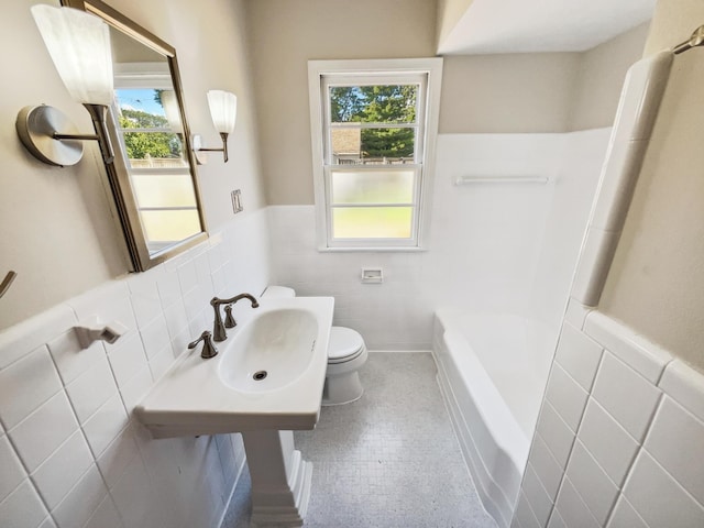 bathroom featuring a healthy amount of sunlight, tile walls, toilet, and sink