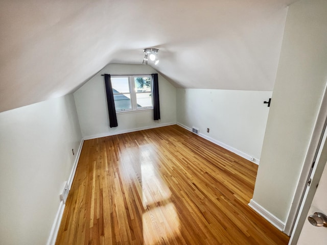 additional living space featuring wood-type flooring and lofted ceiling