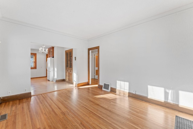 unfurnished room with crown molding, light hardwood / wood-style flooring, and a notable chandelier