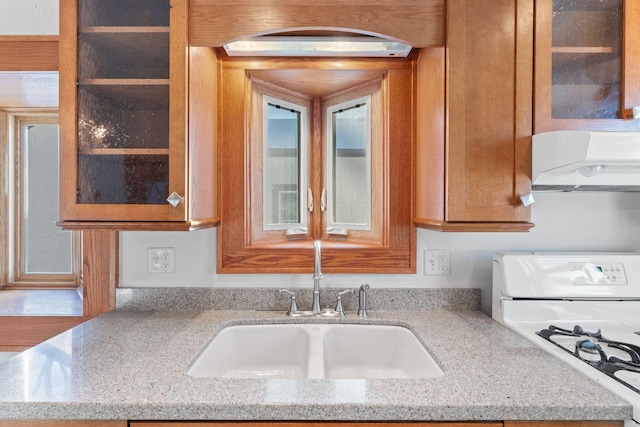 kitchen featuring sink, white gas range oven, and light stone countertops