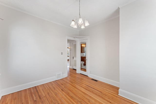 empty room with an inviting chandelier, crown molding, and light hardwood / wood-style flooring