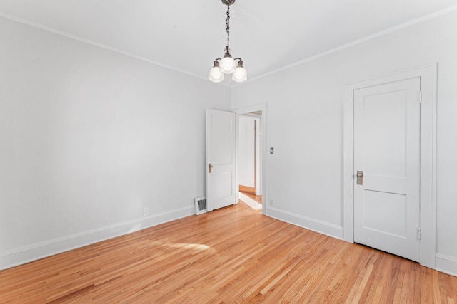 spare room with ornamental molding, a chandelier, and hardwood / wood-style floors