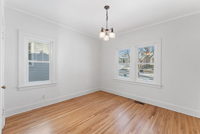 empty room featuring light wood-type flooring, a chandelier, and ornamental molding