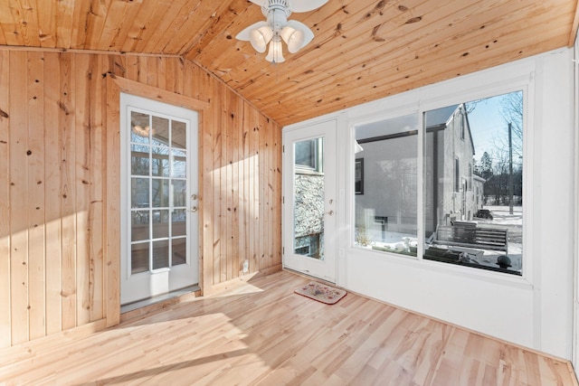 doorway featuring wood walls, hardwood / wood-style floors, lofted ceiling, and ceiling fan