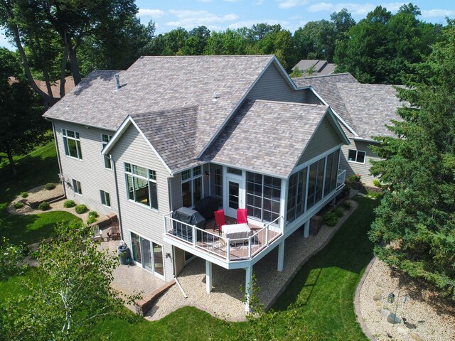 rear view of house with a yard, a shingled roof, a patio area, and a sunroom