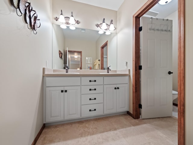 bathroom featuring toilet, a sink, and double vanity