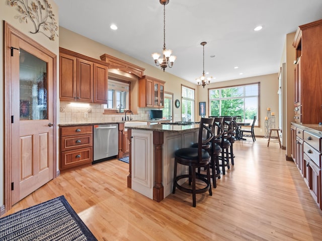 4424 Donway Dr NE, Alexandria, MN 56308 - kitchen with dishwasher, brown cabinetry, a kitchen island, light wood-style floors, and a kitchen breakfast bar
