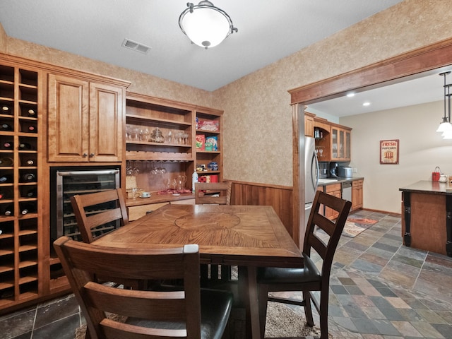 4424 Donway Dr NE, Alexandria, MN 56308 - dining space featuring wainscoting, bar, dark stone finish flooring, and beverage cooler