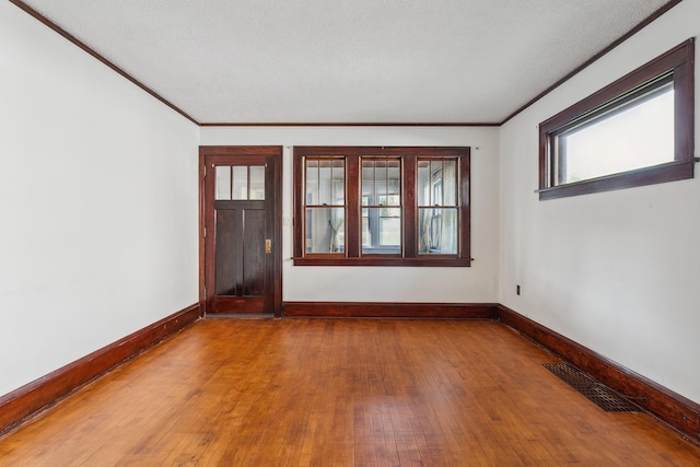 spare room featuring a textured ceiling, ornamental molding, and hardwood / wood-style flooring