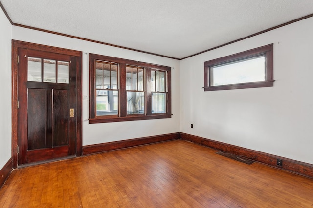 foyer featuring a textured ceiling, ornamental molding, and hardwood / wood-style floors