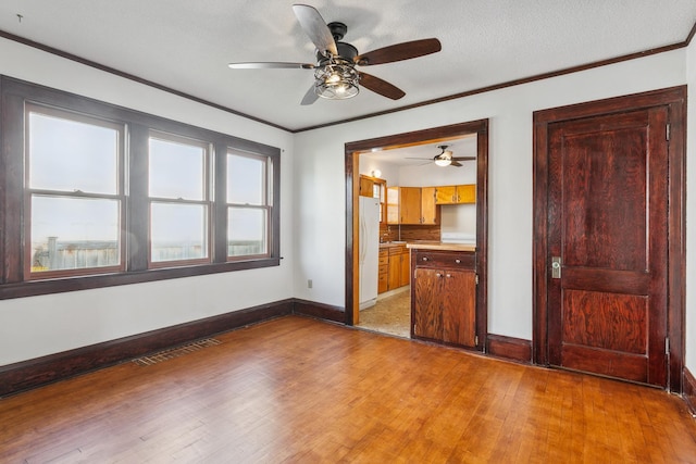 unfurnished bedroom with a textured ceiling, white fridge, wood-type flooring, connected bathroom, and ceiling fan