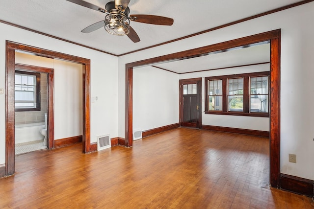 spare room with hardwood / wood-style floors, ceiling fan, crown molding, and a textured ceiling