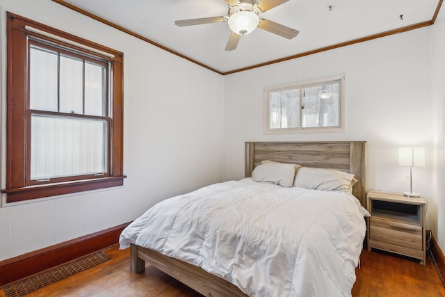 bedroom with dark wood-type flooring, ceiling fan, and crown molding