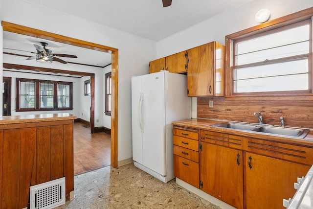 kitchen featuring crown molding, light hardwood / wood-style flooring, sink, white fridge, and ceiling fan