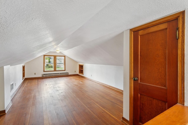 additional living space with a textured ceiling, wood-type flooring, a baseboard radiator, and lofted ceiling