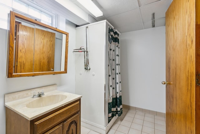 bathroom with tile patterned flooring, walk in shower, a drop ceiling, and vanity