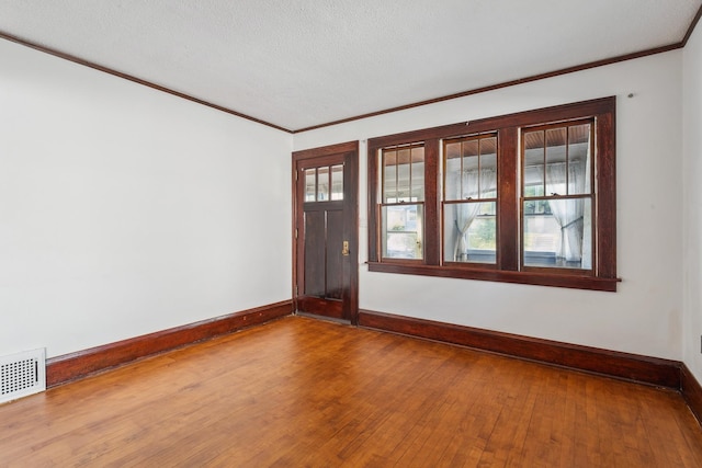 spare room with crown molding, a textured ceiling, and hardwood / wood-style flooring