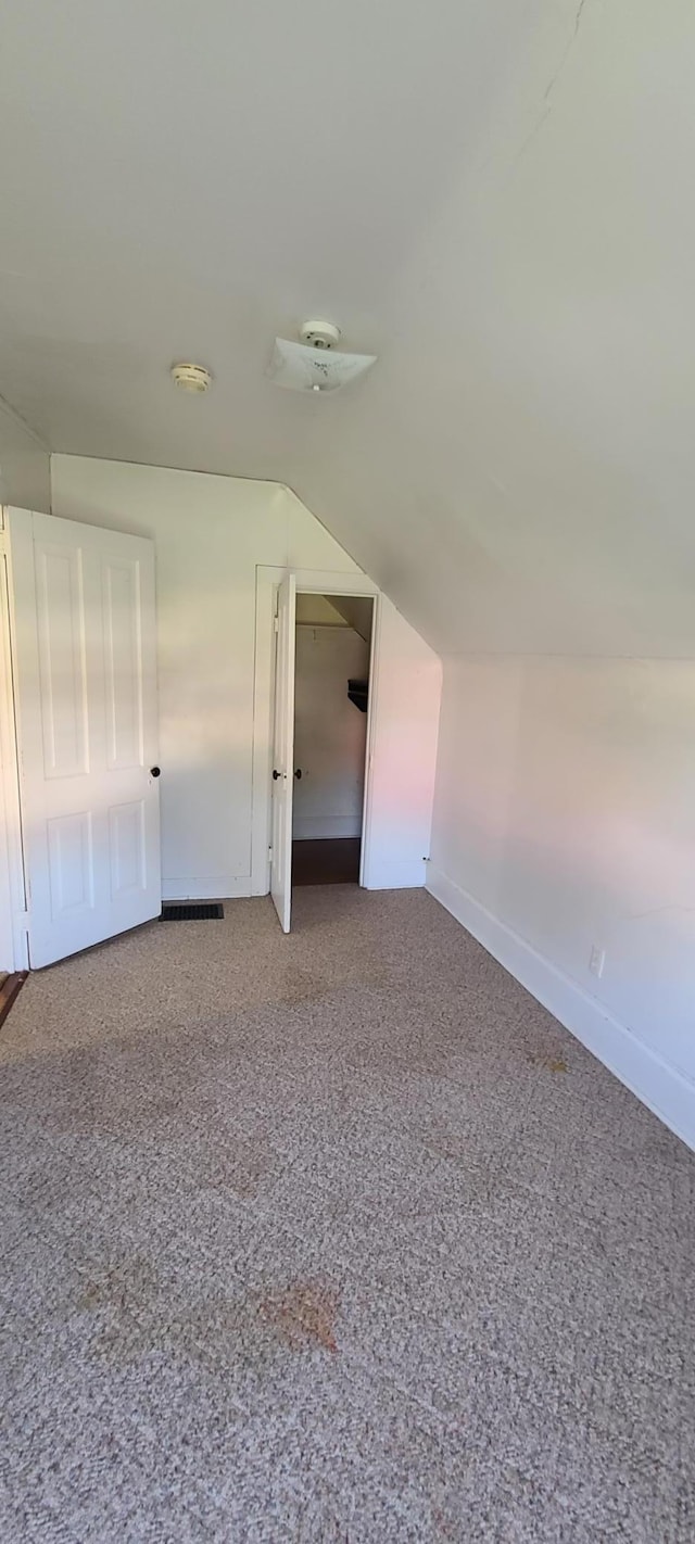 additional living space with vaulted ceiling and carpet floors