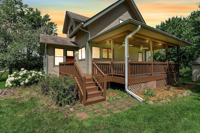 back house at dusk featuring a deck and ceiling fan