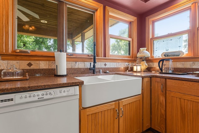 kitchen featuring dark stone countertops, white dishwasher, and sink