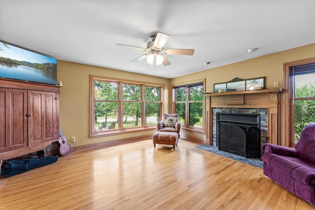 living room featuring a healthy amount of sunlight, ceiling fan, light wood-type flooring, and a fireplace