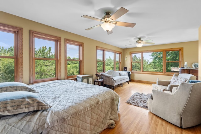 bedroom with ceiling fan, multiple windows, and light hardwood / wood-style floors