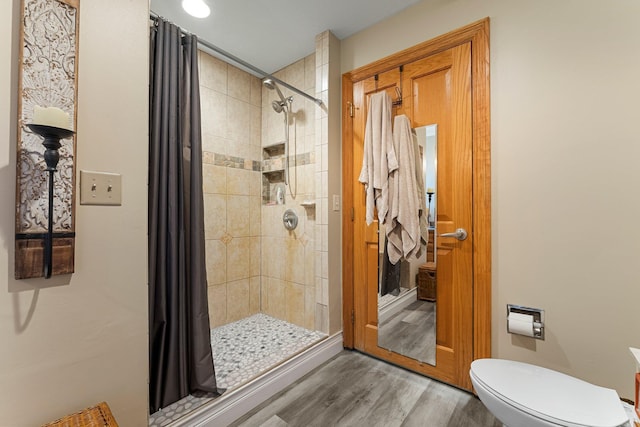 bathroom featuring tiled shower, toilet, and hardwood / wood-style flooring