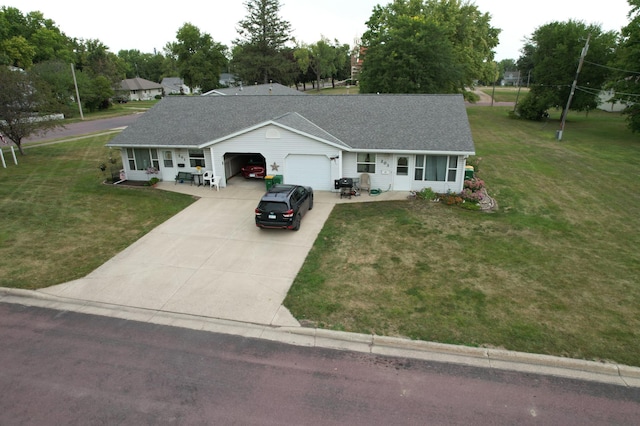 ranch-style house with an attached garage, concrete driveway, a shingled roof, and a front yard