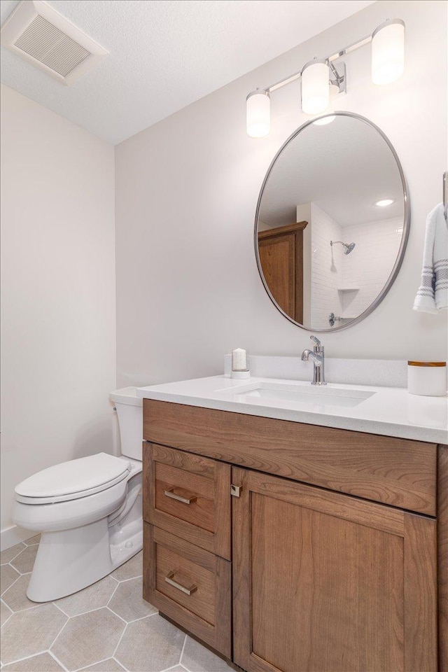 bathroom featuring tile patterned floors, toilet, a textured ceiling, and vanity