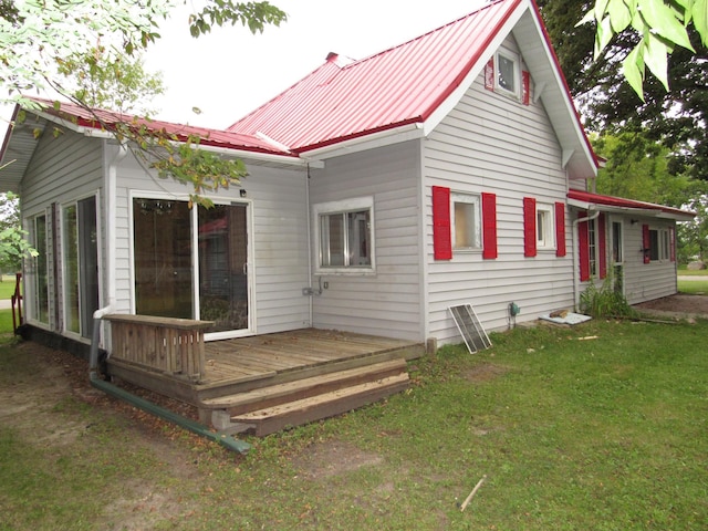 back of property featuring a lawn, a wooden deck, and metal roof