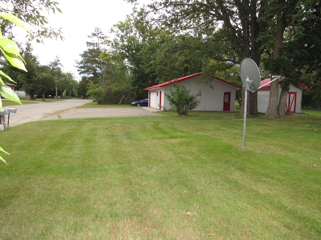 view of yard featuring a garage, an outbuilding, and driveway