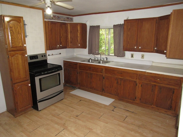 kitchen with stainless steel electric range oven, ornamental molding, sink, ceiling fan, and light wood-type flooring