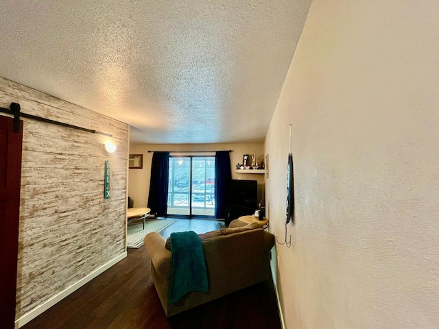 living room featuring a barn door, dark wood-type flooring, and a textured ceiling