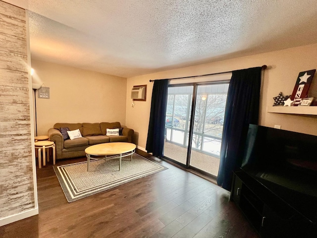 living room with a textured ceiling, dark wood-type flooring, and a wall mounted air conditioner