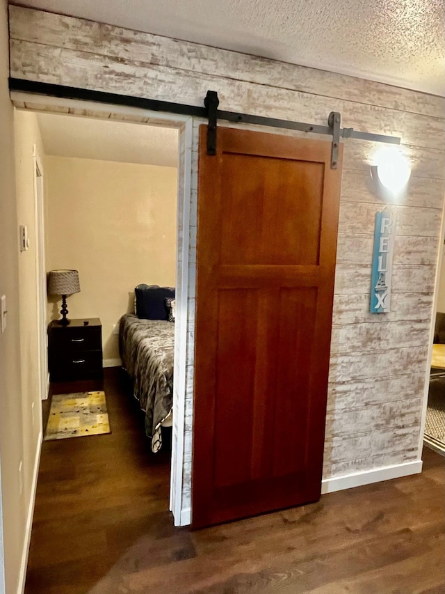 bedroom featuring a textured ceiling, a barn door, and dark hardwood / wood-style flooring