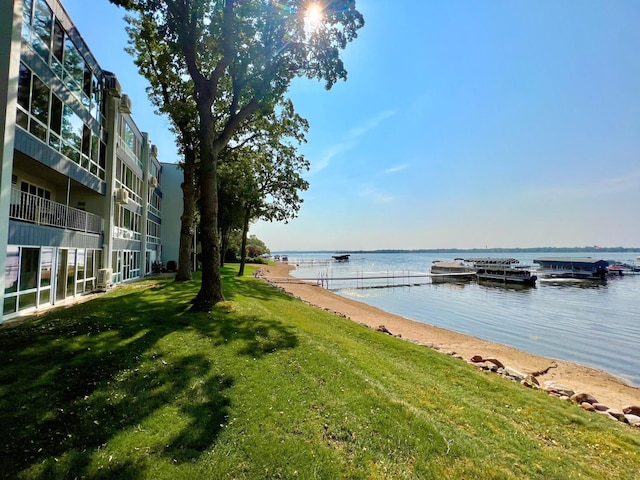 dock area featuring a balcony, a lawn, and a water view