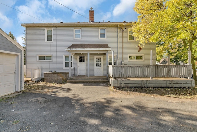 rear view of property with a garage and a deck