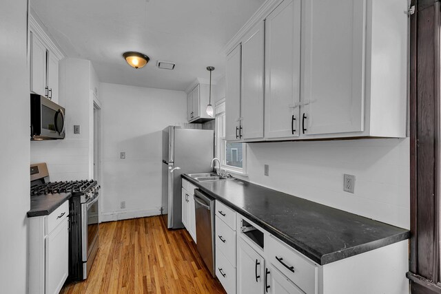 kitchen with sink, stainless steel appliances, light hardwood / wood-style floors, white cabinets, and decorative light fixtures