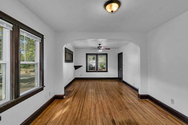 unfurnished room featuring ceiling fan, wood-type flooring, and a wealth of natural light