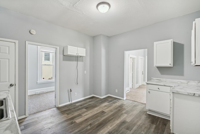 unfurnished dining area with dark wood-type flooring and a textured ceiling