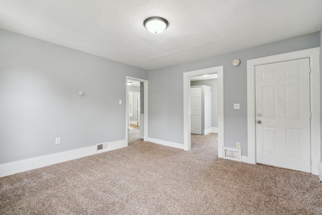 carpeted empty room featuring a textured ceiling