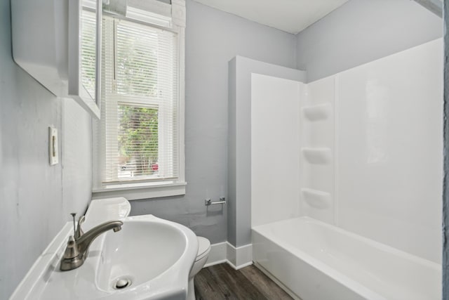 full bathroom with hardwood / wood-style floors, toilet,  shower combination, and sink