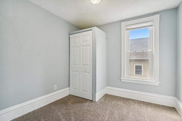 unfurnished bedroom featuring a textured ceiling, a closet, and carpet floors